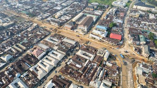 Aerial view of a dense urban sprawl with a mix of residential and commercial buildings under a bright sky, Onitsha, Anambra, Nigeria.