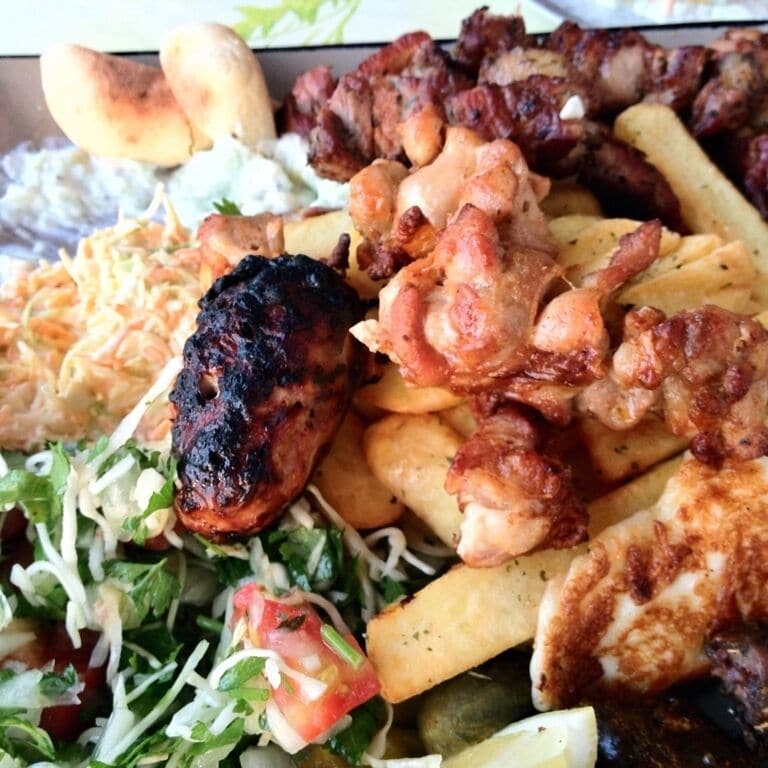 A plate of grilled meats, fries, and a salad.