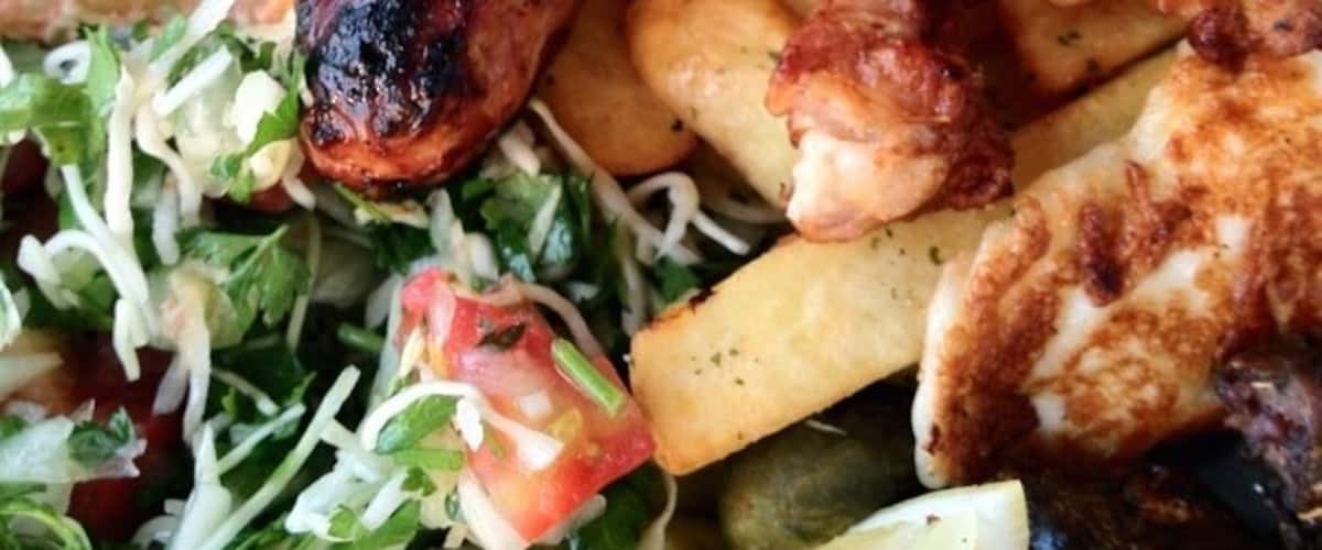 A plate of grilled meats, fries, and a salad.