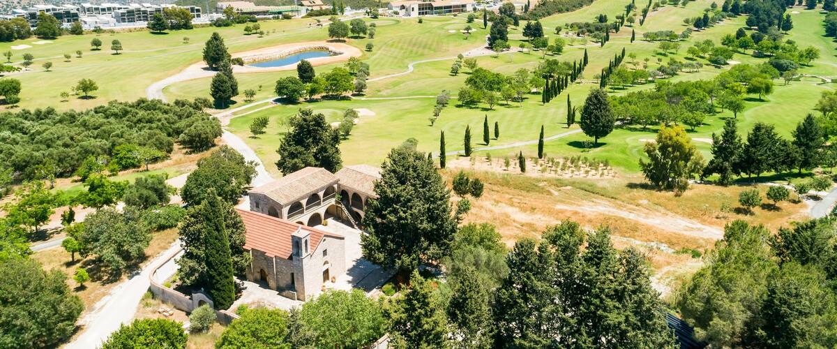 A golf course with a stone building and a view of distant hills.