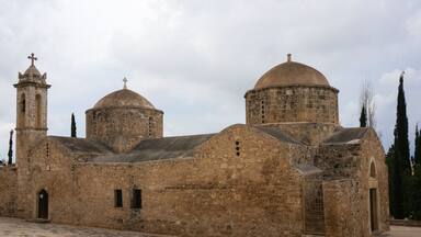 A historic stone church with two domes and a bell tower.