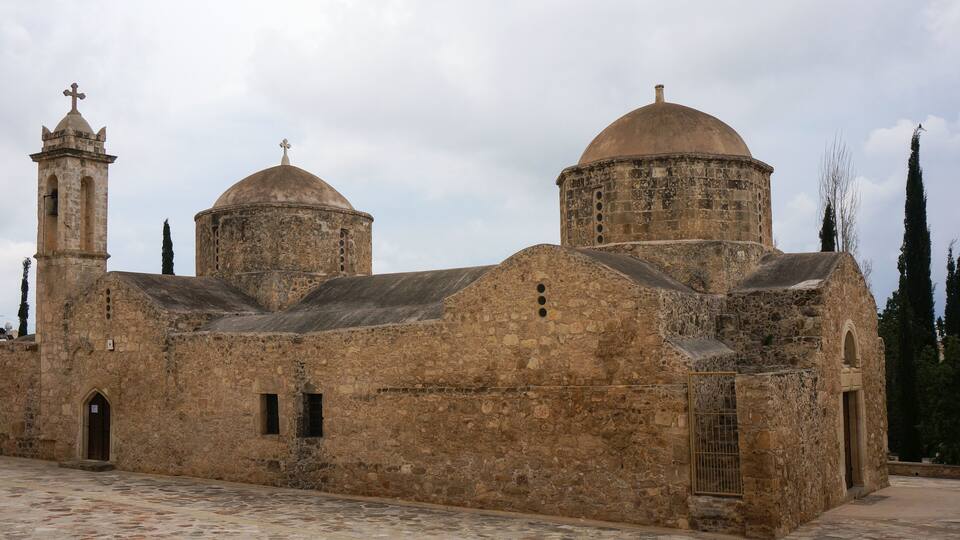 A historic stone church with two domes and a bell tower.