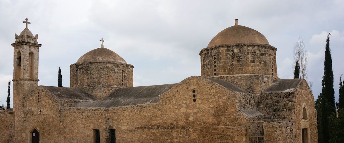 A historic stone church with two domes and a bell tower.