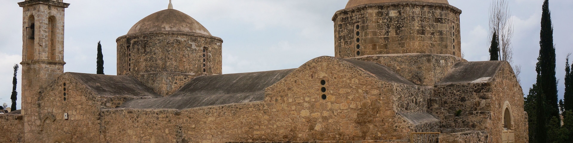 A historic stone church with two domes and a bell tower.