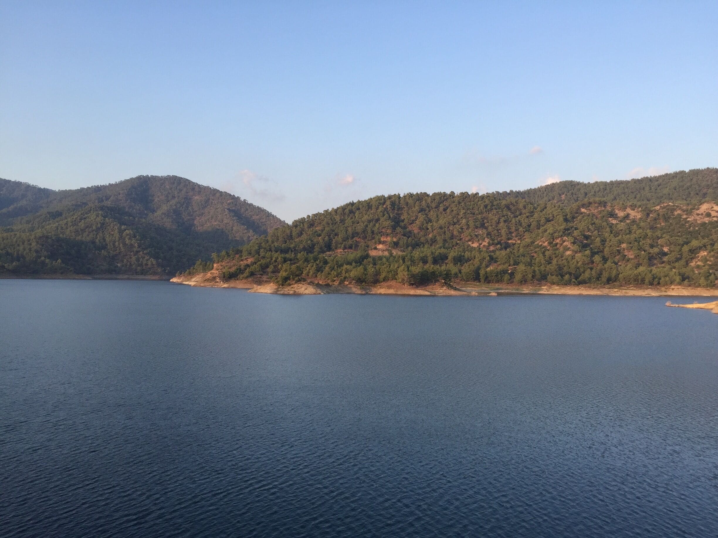 A calm lake surrounded by forested hills.