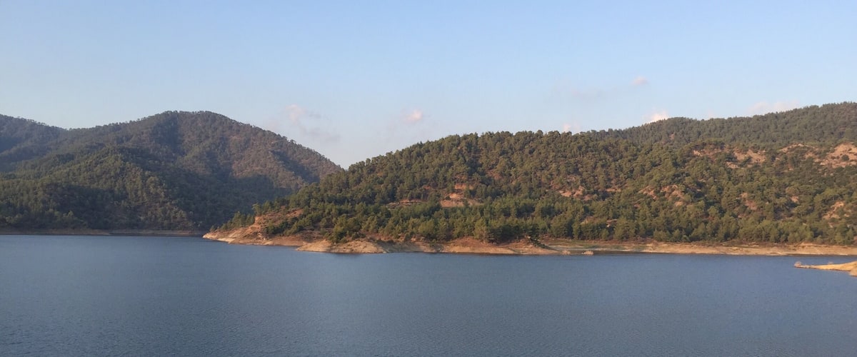 A calm lake surrounded by forested hills.