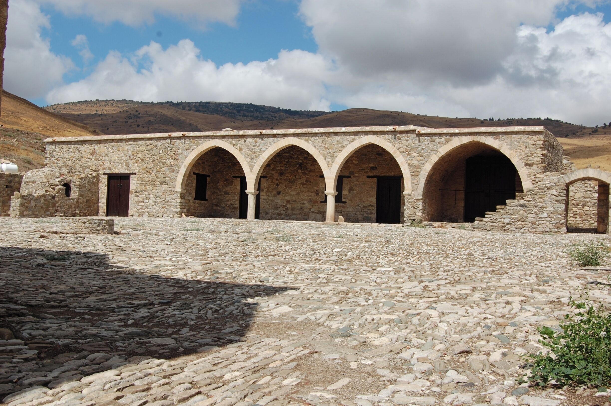 A stone building with arched doorways and a cobblestone courtyard.