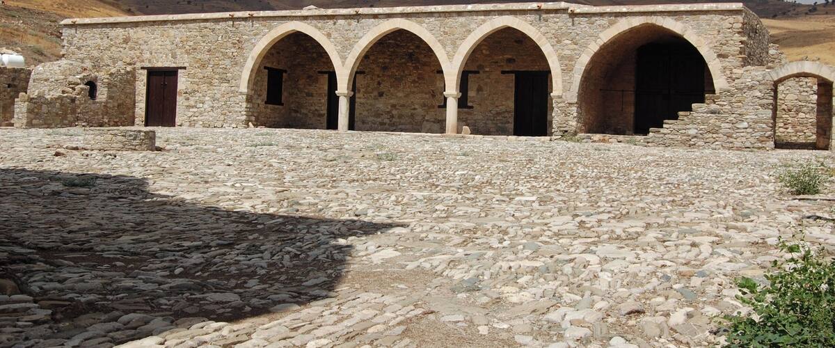 A stone building with arched doorways and a cobblestone courtyard.