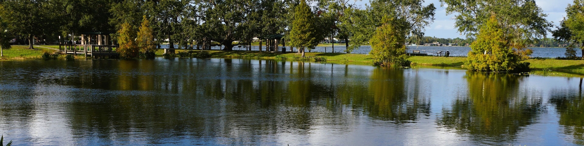 A peaceful park setting with a calm pond reflecting the surrounding trees and sky near Lake Hartridge Nature Park, Winter Haven, Florida, U.S