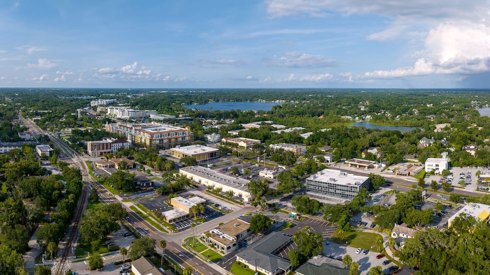 An aerial view of a city with a river, buildings, and green spaces.