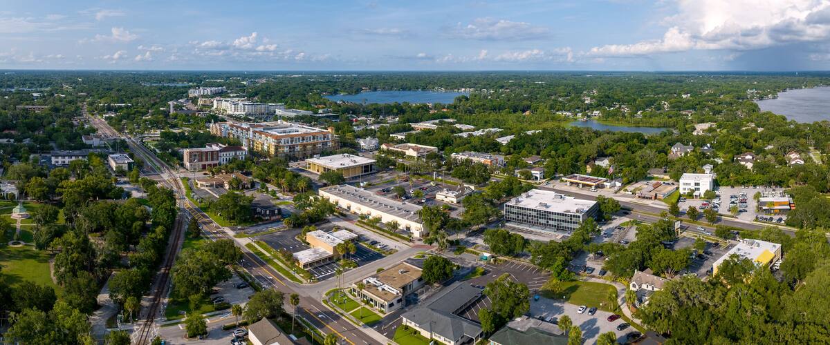 An aerial view of a city with a river, buildings, and green spaces.