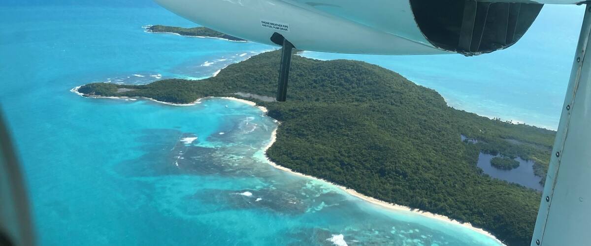 An aerial view of a tropical island with clear turquoise waters and a sandy beach.