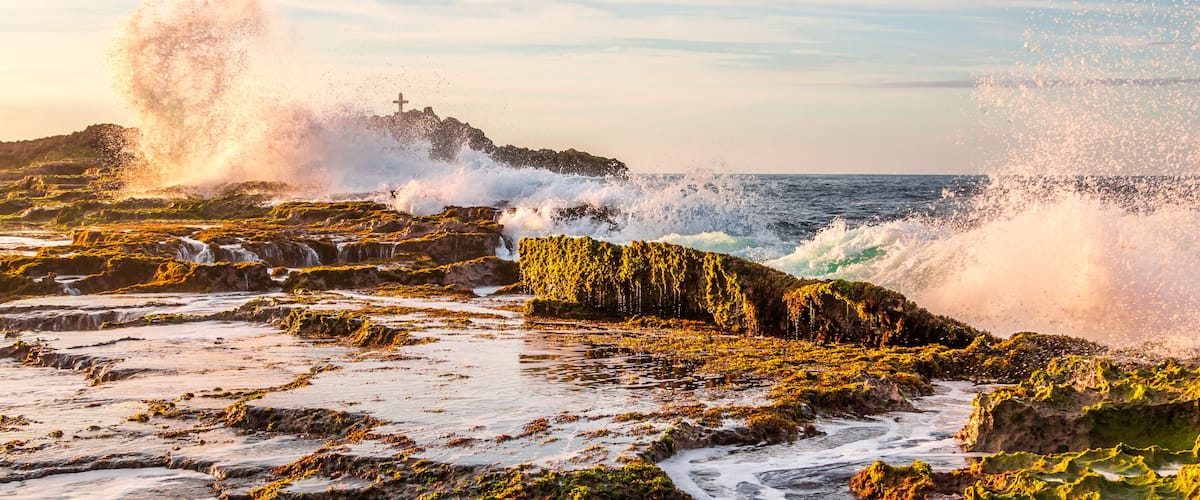 Una costa rocosa con olas rompiendo contra las rocas.
