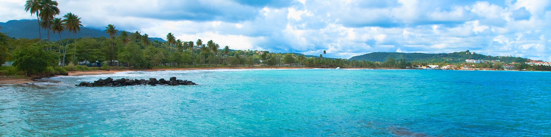 San Juan, Puerto Rico - Calm water is seen in the bay of a tropic island. Trees and beach can be seen in the background.