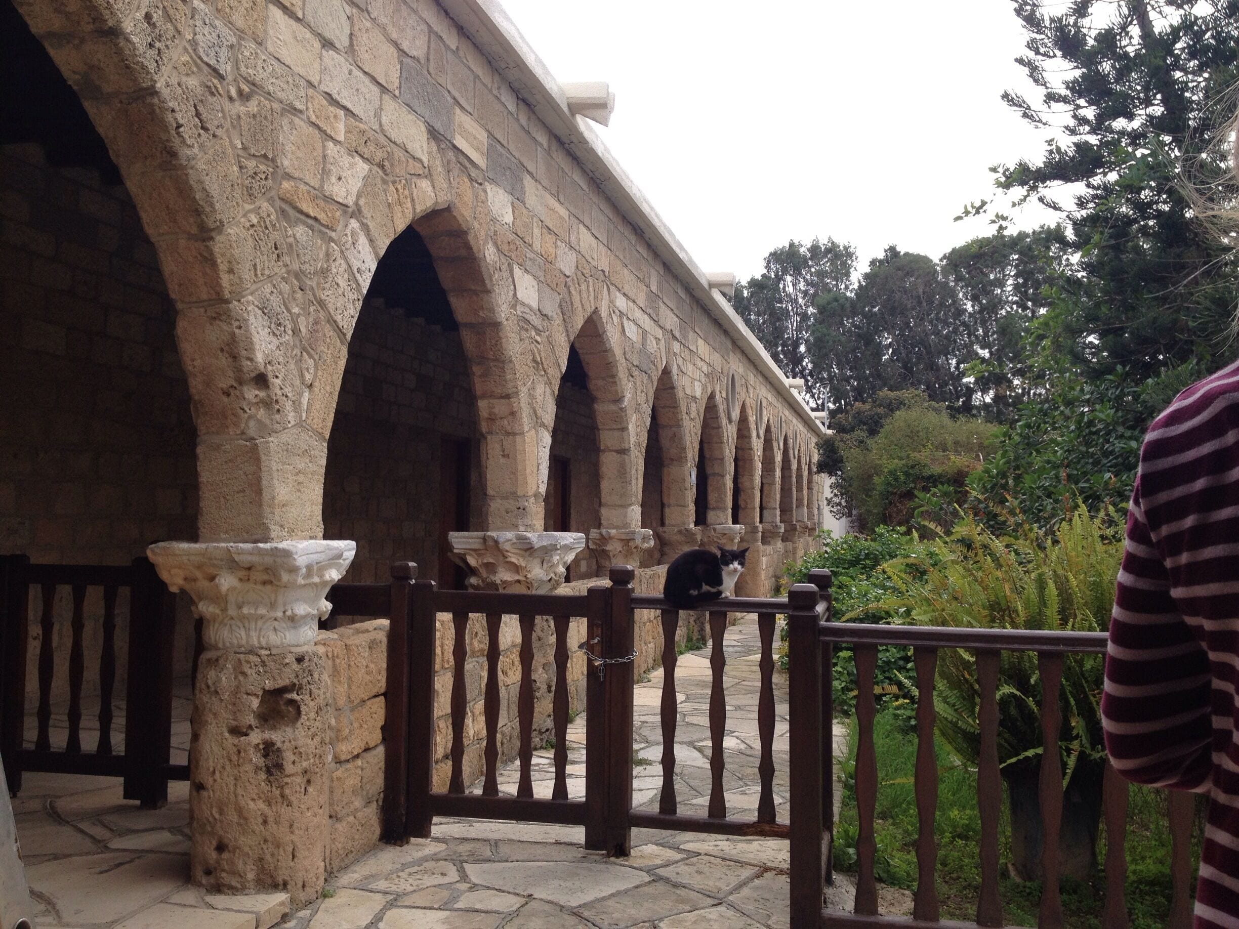 An ancient stone bridge with multiple arches, a stone pathway, and lush greenery in the background.
