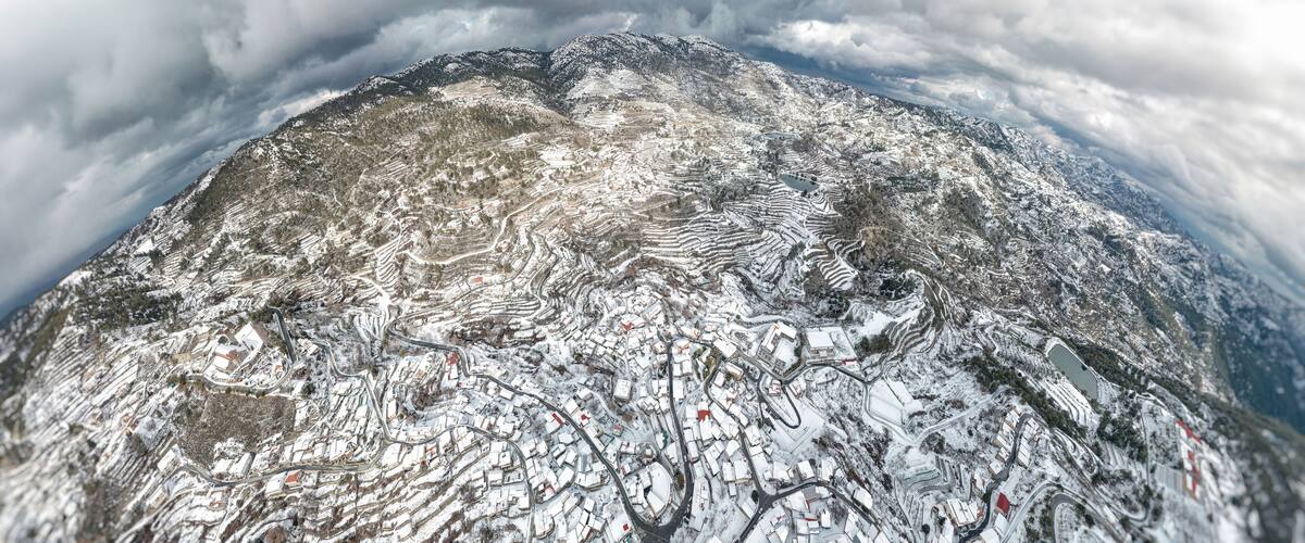 A snow-covered mountainous landscape with winding roads and buildings.