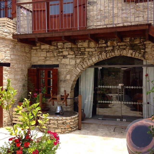 A stone building with a wooden balcony, a glass door, and a stone archway.