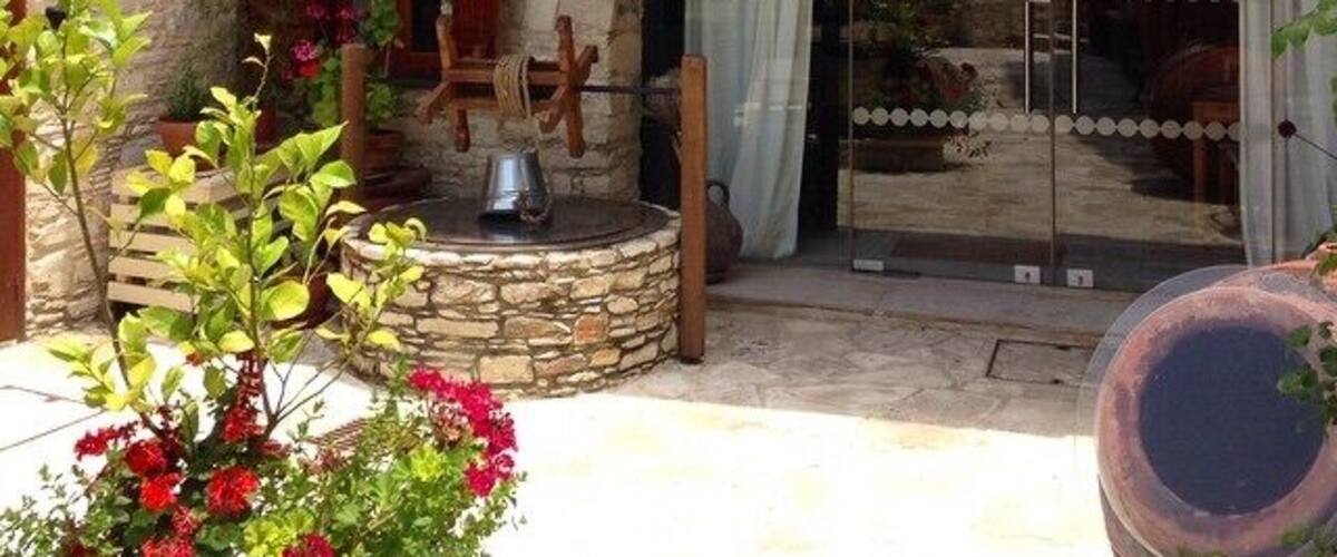 A stone building with a wooden balcony, a glass door, and a stone archway.
