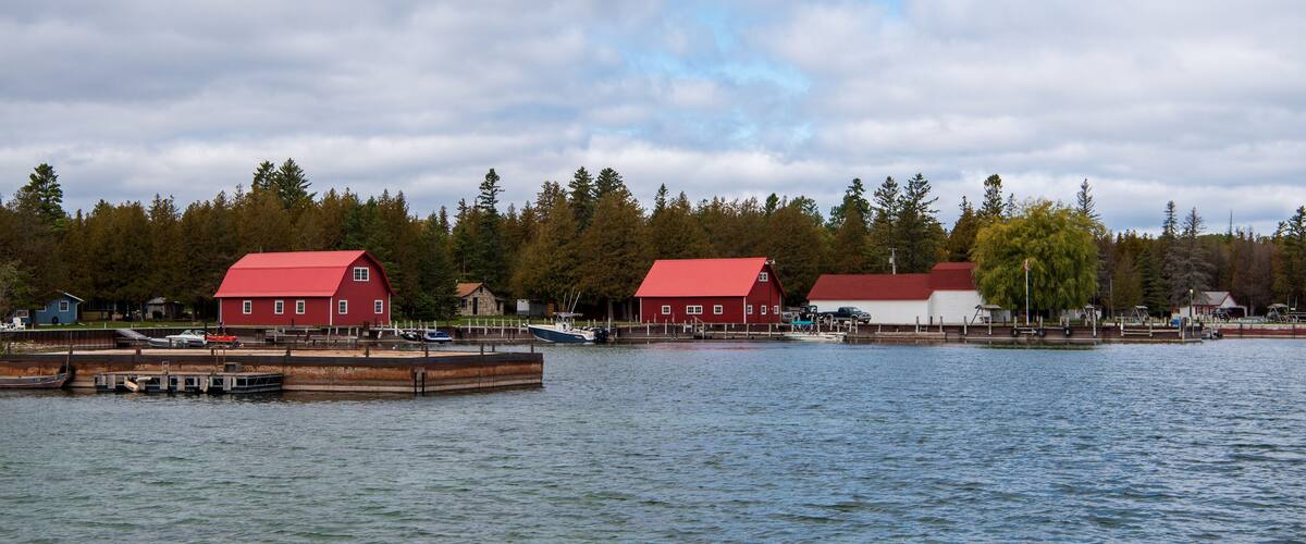 A lake with two red buildings and a dock.