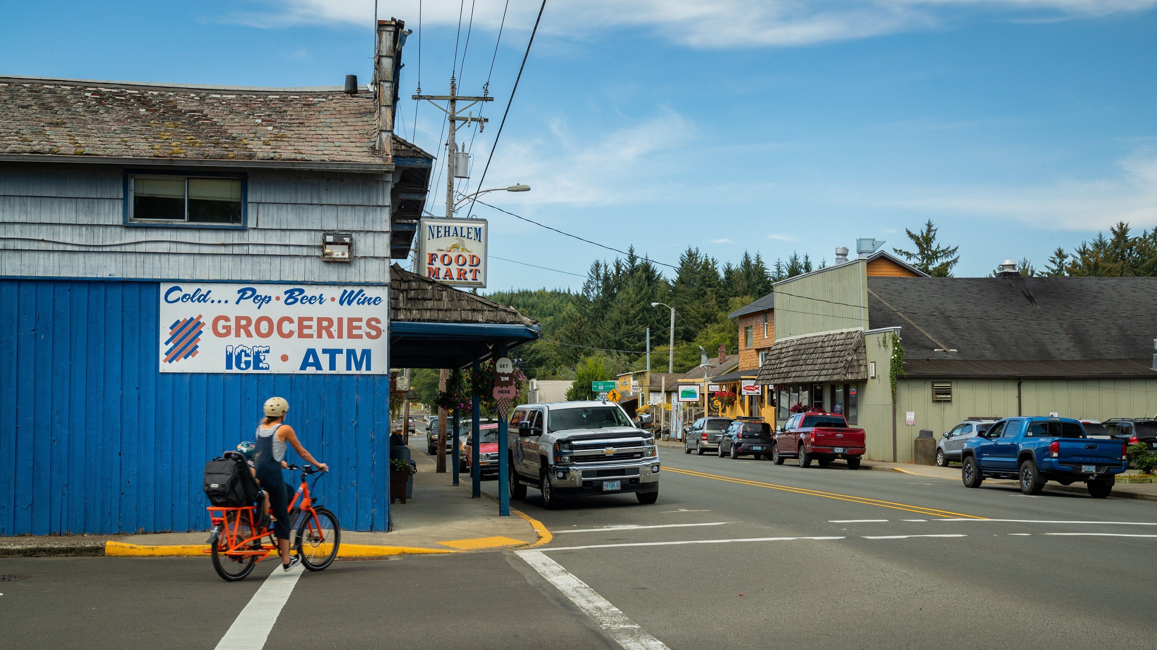 A street scene with a blue building labeled "Groceries" and "Cold... Pop... Beer... Wine."
