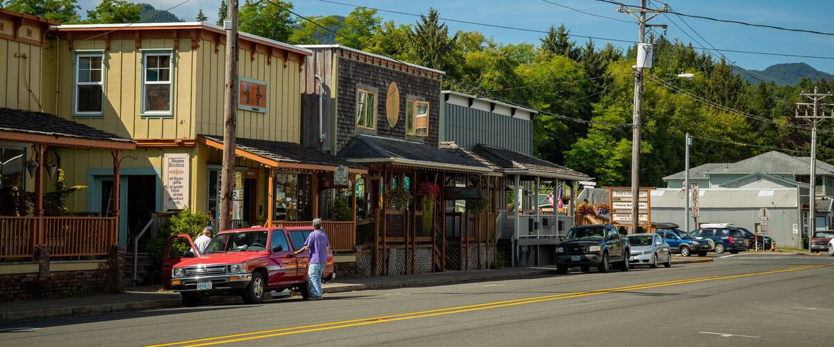 A street lined with wooden buildings, a red truck parked on the side, and a clear blue sky.
