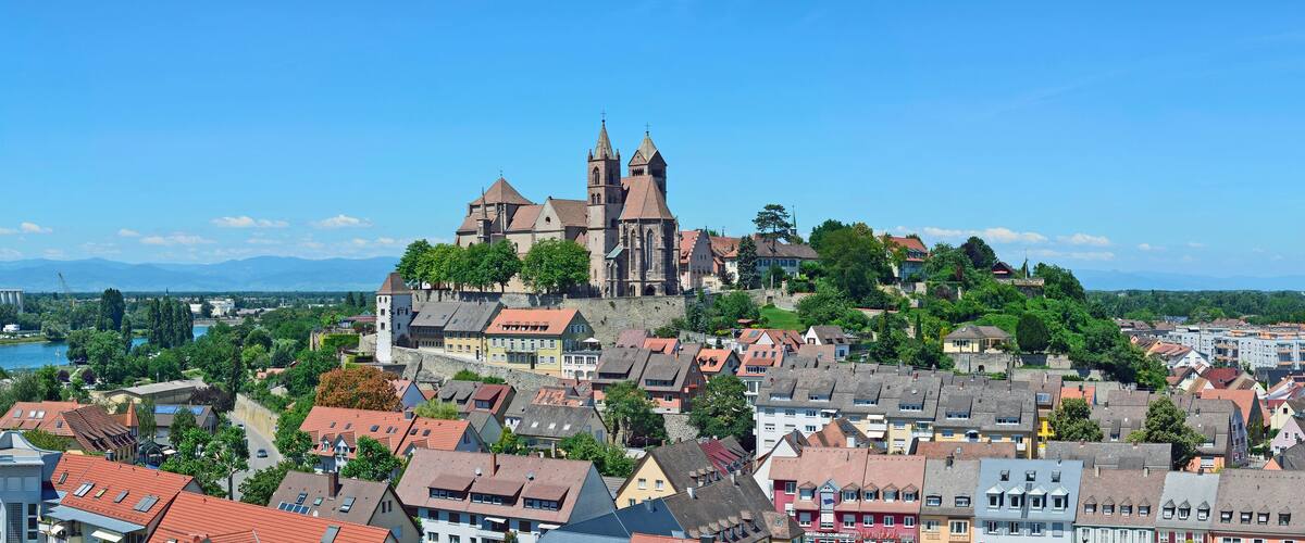 A historic town with a prominent church on a hill, surrounded by residential buildings and a river.