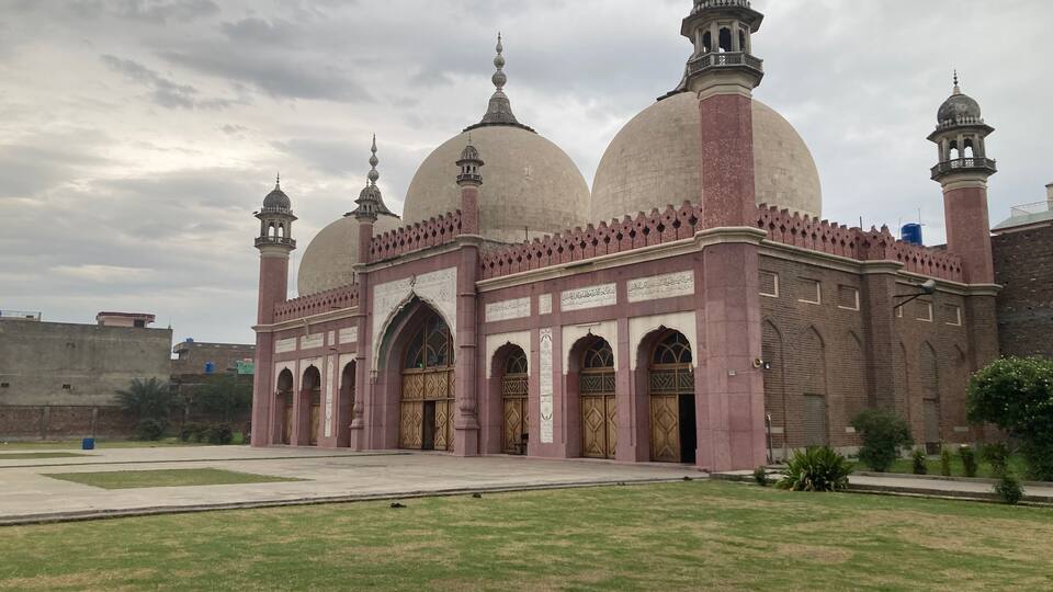 A large mosque with multiple domes and minarets, surrounded by a grassy courtyard.