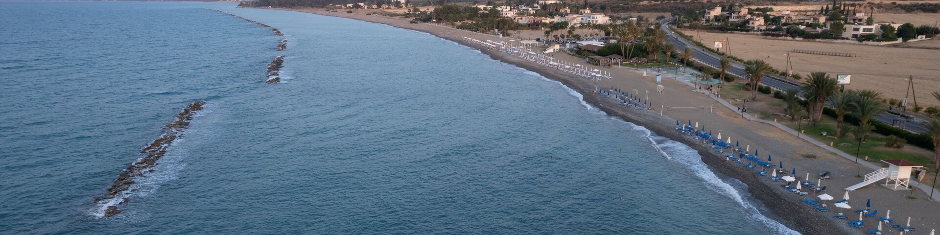 A coastal landscape with a beach, ocean, and distant mountains.