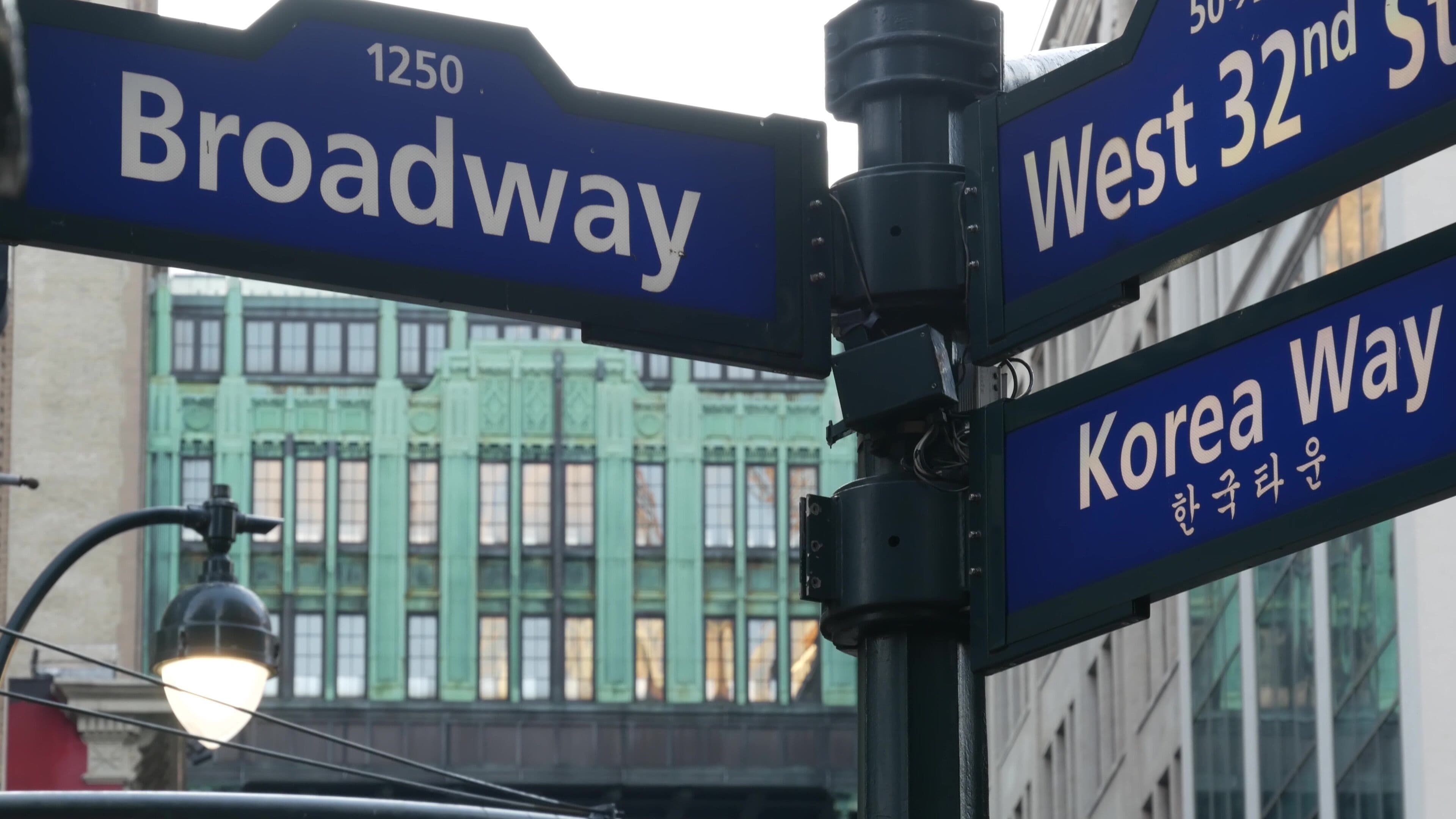 Street signs for Broadway, West 32nd St, and Korea Way.