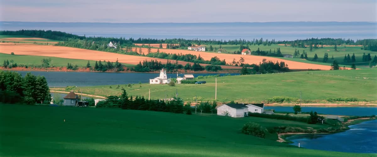 A rural landscape with a church, fields, and a lake.