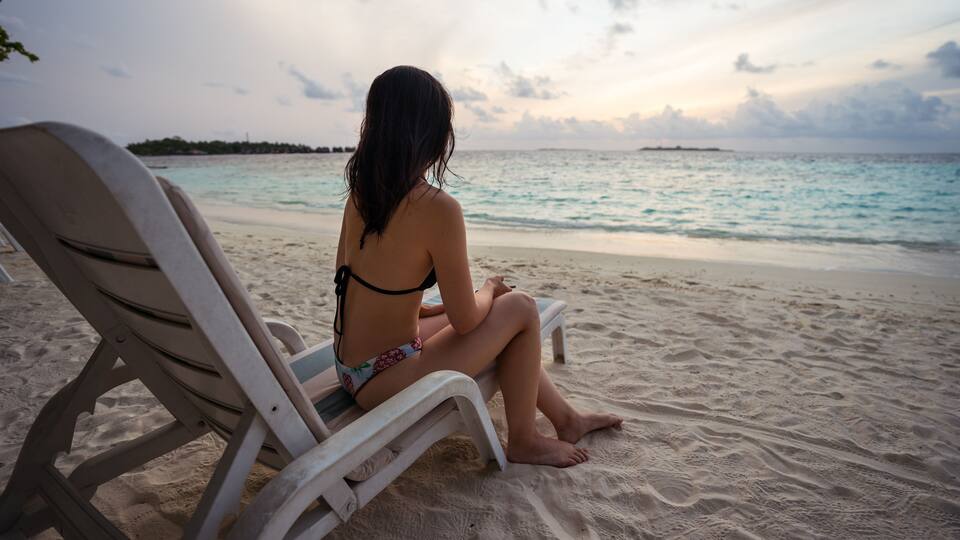 A person sitting on a beach chair facing the ocean.