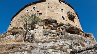 A historic stone tower with a circular base, perched on rocky terrain.