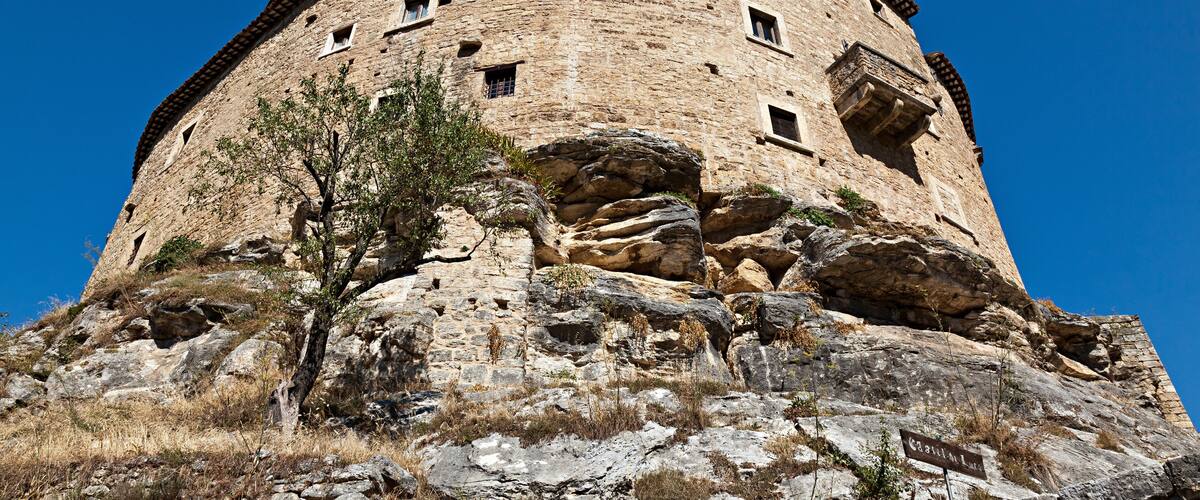 A historic stone tower with a circular base, perched on rocky terrain.