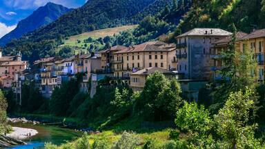 A picturesque village with a river, surrounded by lush greenery and mountains.