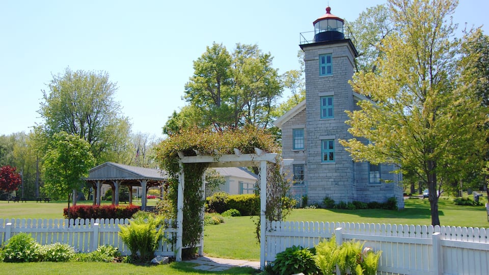 A stone building with a tower, a white picket fence, and a gazebo.