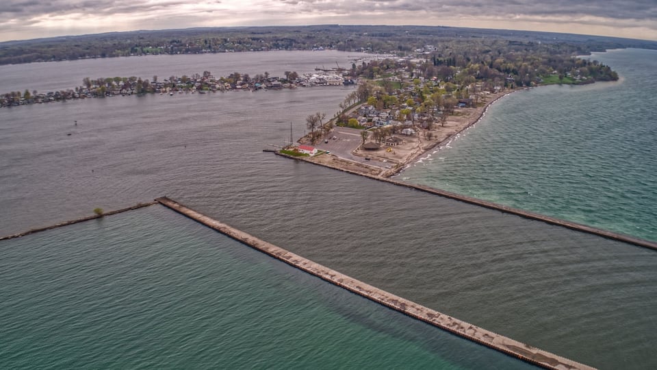 An aerial view of a coastal town with a pier extending into the water, surrounded by a mix of residential and industrial buildings.