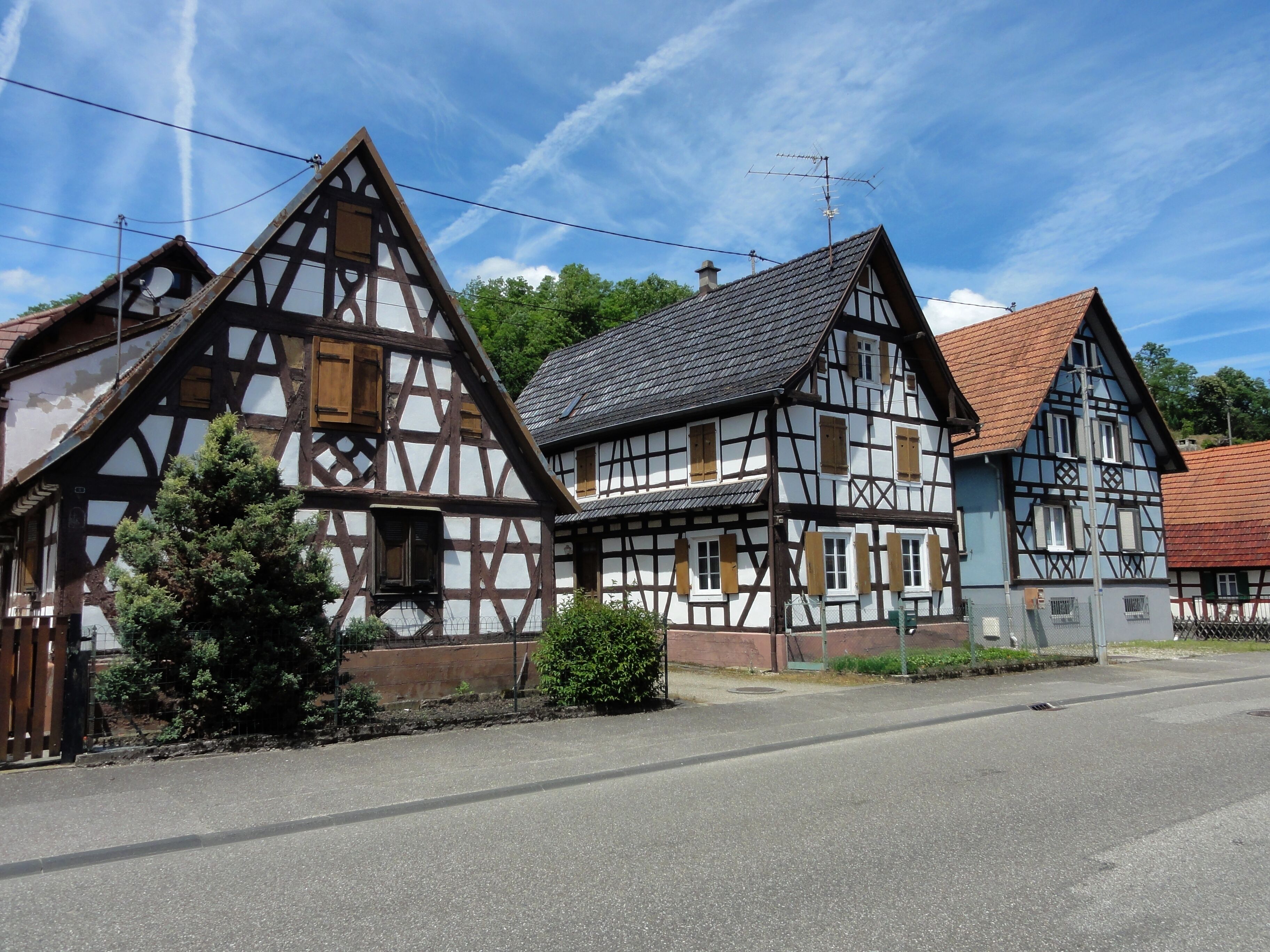 A row of traditional half-timbered houses with a clear sky and a road in front.