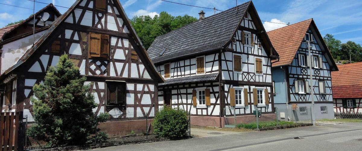 A row of traditional half-timbered houses with a clear sky and a road in front.