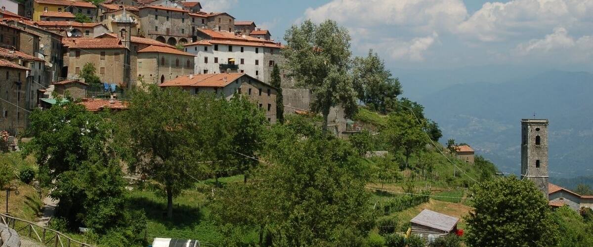 A hillside village with historic buildings and a prominent tower.