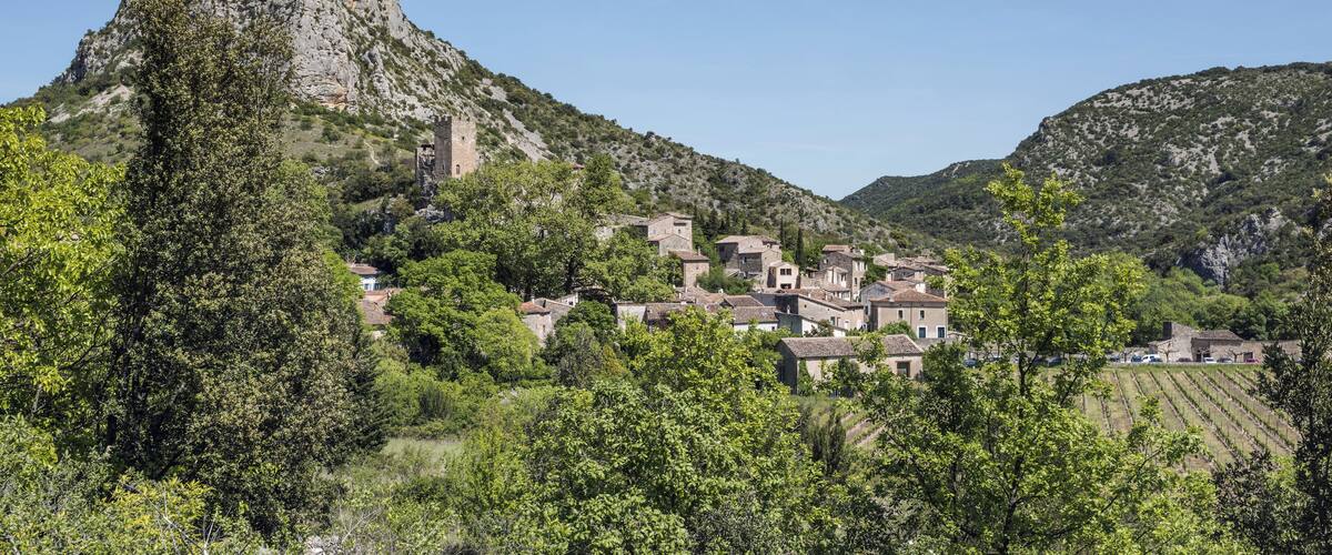 A village nestled in a valley with a prominent rocky hill and a tower.