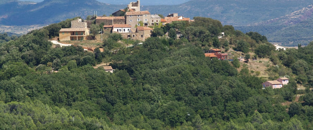 A historic village perched on a hillside with traditional stone buildings and lush greenery.