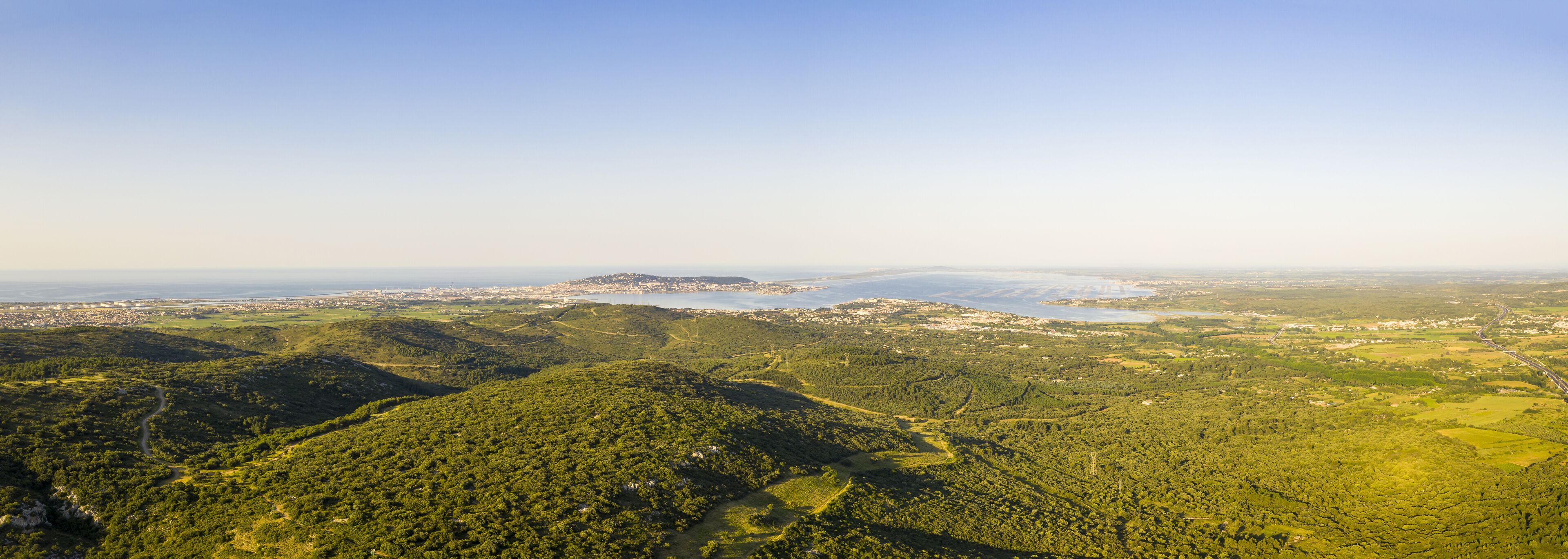 A mountainous landscape with a river and a distant city.