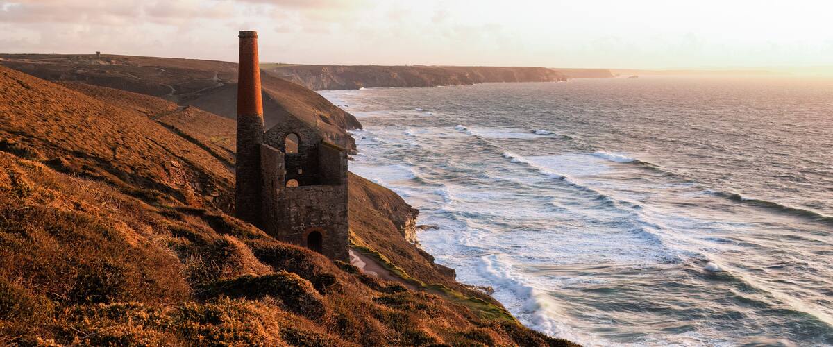 A coastal landscape with a ruined stone structure and cliffs overlooking the sea.