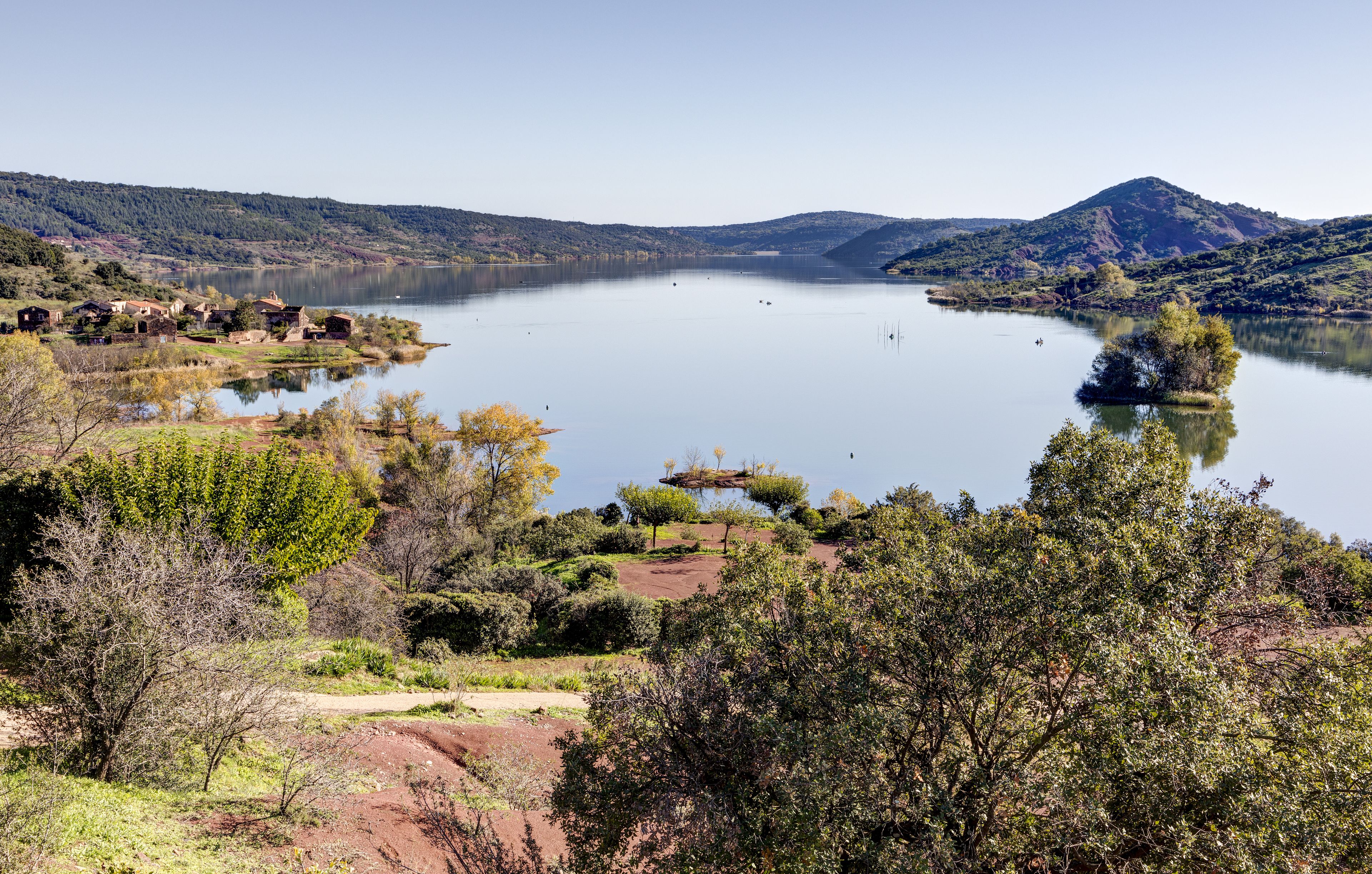 A calm lake surrounded by hills and trees.