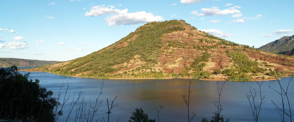 A lake surrounded by hills with sparse vegetation and a clear sky.