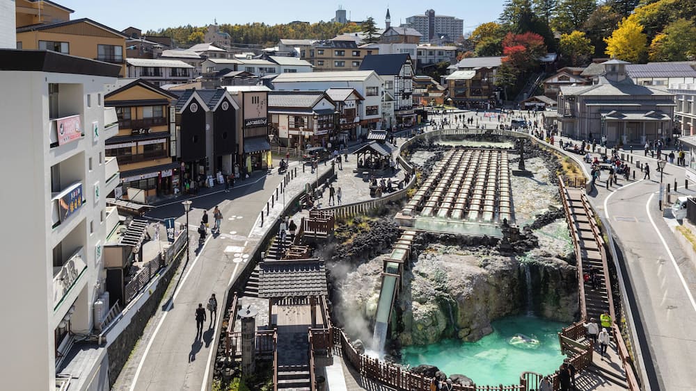 A traditional Japanese town with a hot spring area, including a stone bath and a wooden walkway.