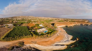 A coastal landscape with a beach, clear waters, and a distant town.