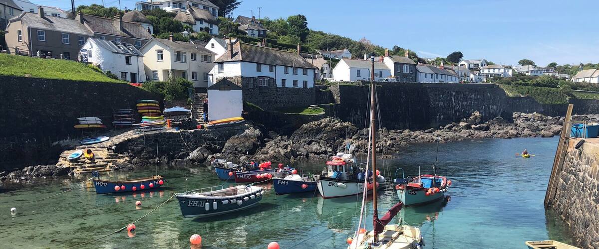A coastal village with clear waters, boats, and houses on a hillside.