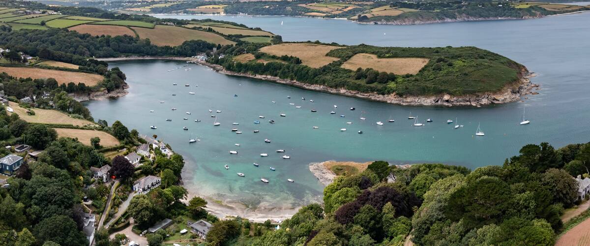 A coastal area with a bay filled with boats, surrounded by lush greenery and fields.