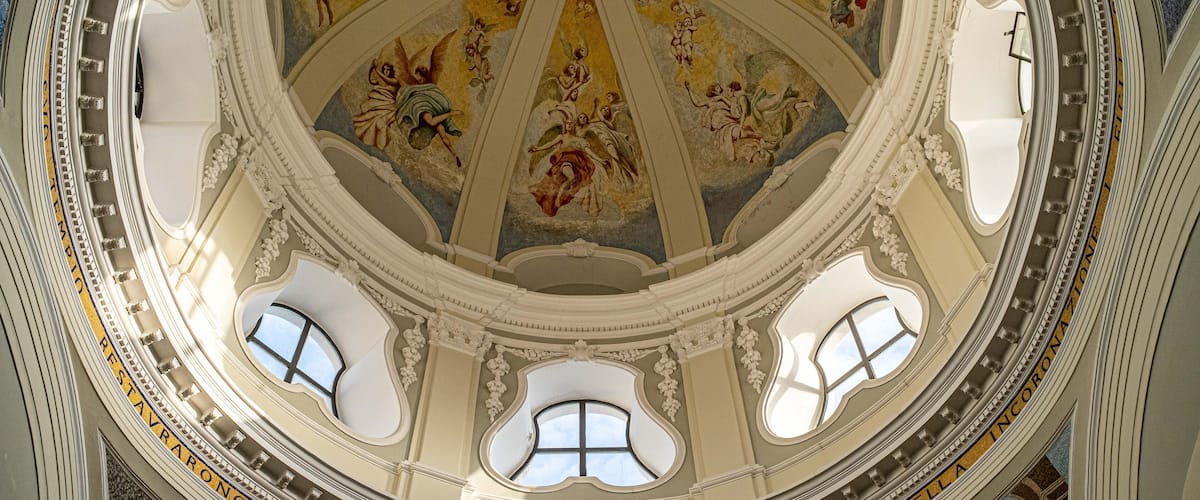 A domed ceiling with frescoes and inscriptions, including "SANTO 1974 CINOVANTE."